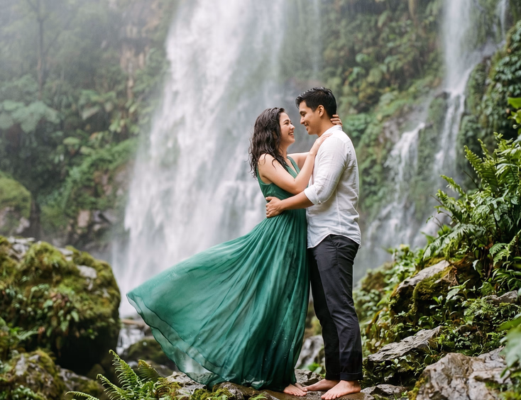 Filipino couple sharing a quiet moment under a misty waterfall during a Philippine highlands prenup shoot.