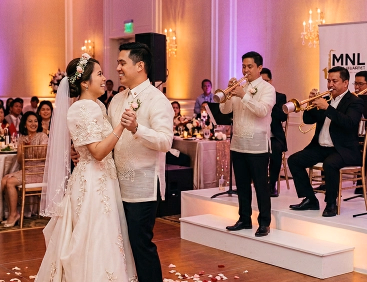 Filipino bride and groom sharing their first dance while a brass quartet performs on stage behind them with rose petals on the dance floor