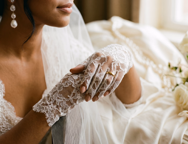 Close-up of Filipino bride's hands in elbow-length white lace gloves with gold wedding band visible through ring finger slit, soft warm side lighting, intimate detail editorial bridal photography
