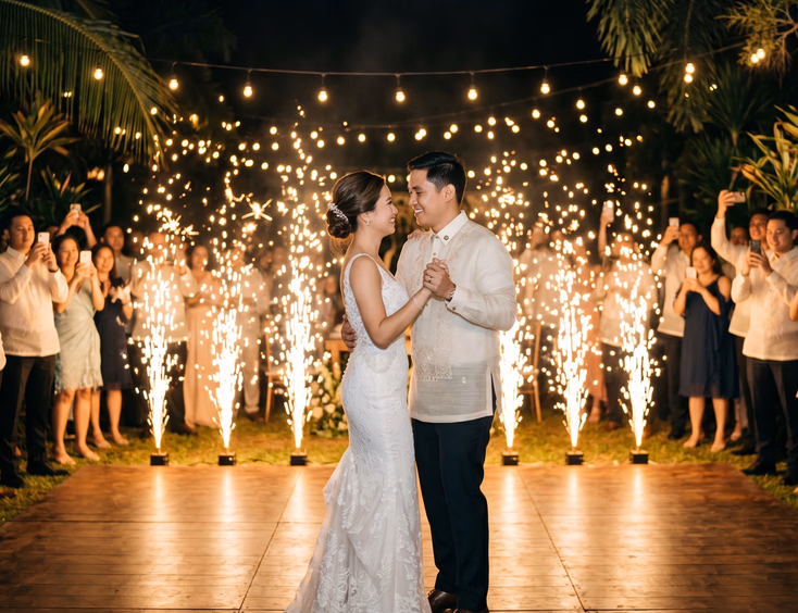 Filipino bride and groom in barong tagalog performing their first dance with a backdrop of firing gold ground gerbs at a wedding reception.
