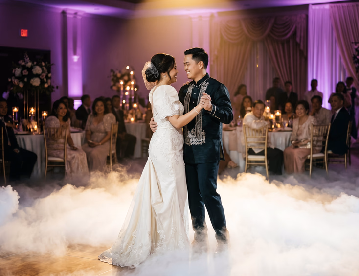 Filipino bride and groom first dance surrounded by low-lying fog with golden spotlight and soft purple uplighting in dimmed reception hall