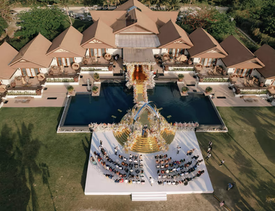 Aerial view of a luxurious Taylor Swift-themed wedding ceremony setup at Balesin Island, with a golden aisle and floral arrangements over a pool.